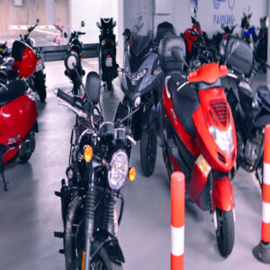 Multiple motorcycles and scooters parked in a parking garage with marked spaces.